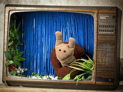 Un monicreque de caracol nunha televisión antiga